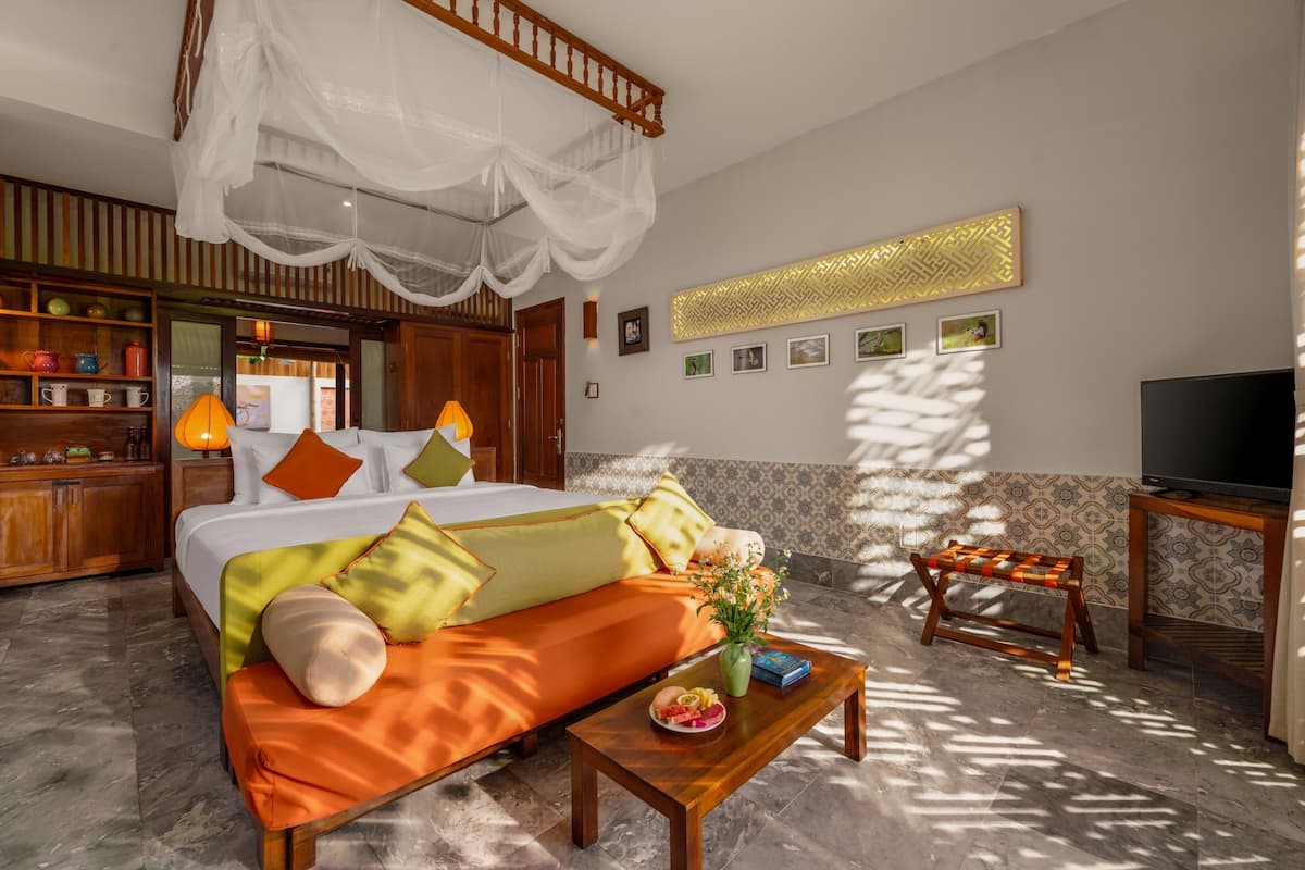 A hotel room with a bed, sofa, bedside table, TV, and a decorative wall panel.