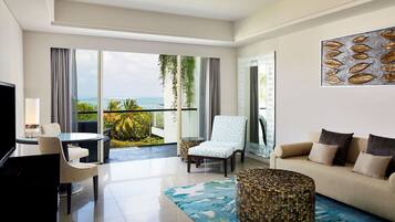 A modern hotel room with a balcony, a sofa, a chair, a coffee table, and a television.