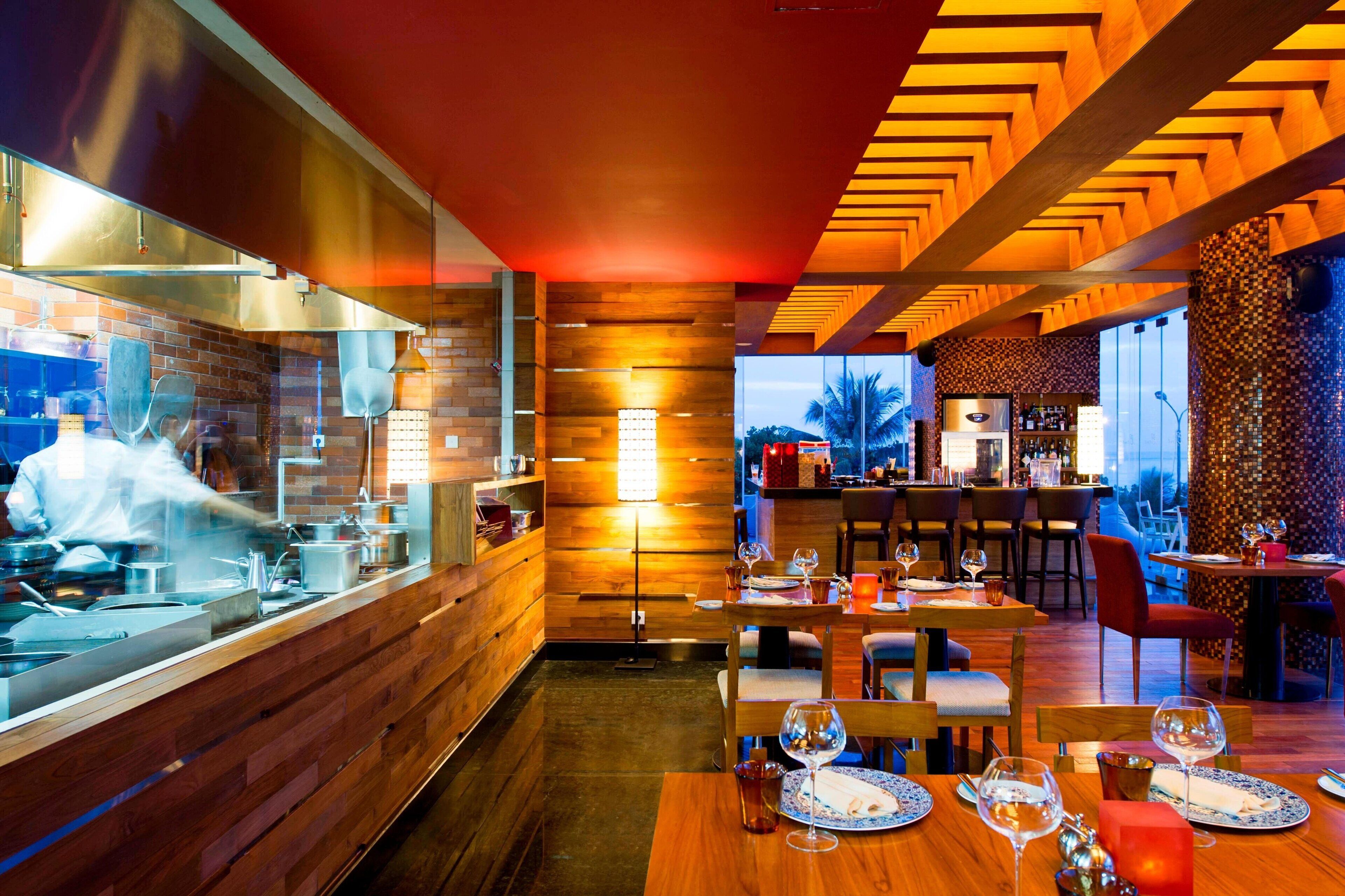 A restaurant with a chef preparing food, wooden walls, and a bar area.