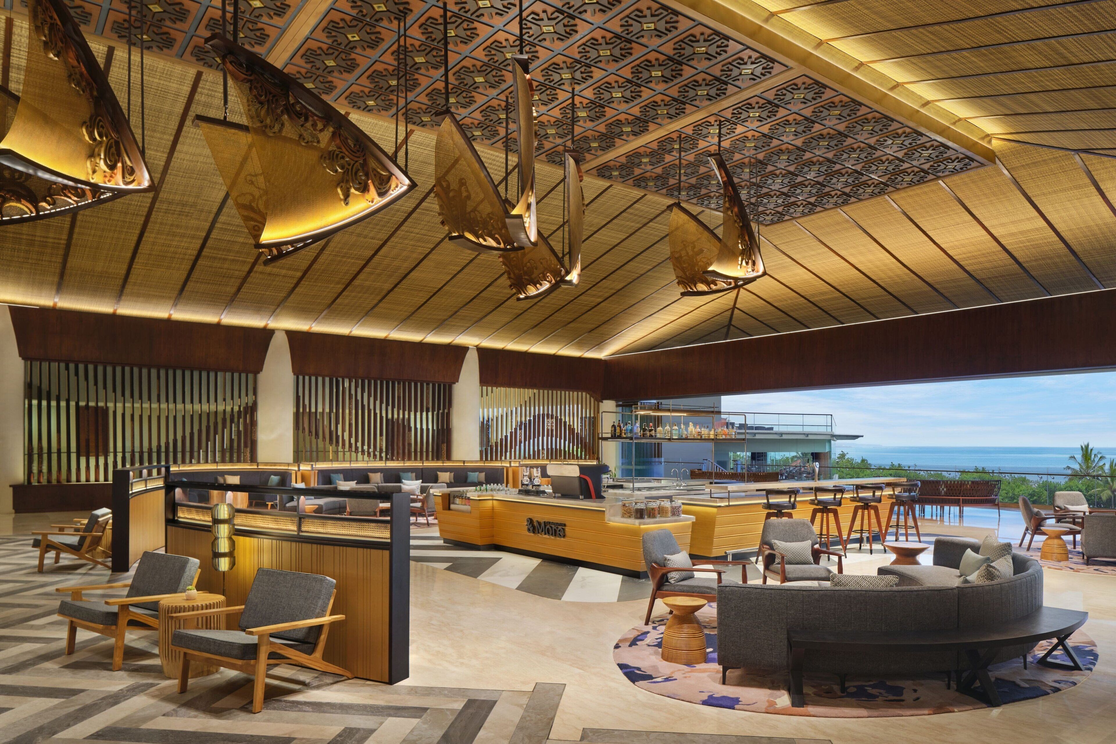 A modern lobby with a reception desk, seating area, and a view of the ocean.