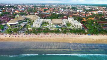 A resort with multiple buildings, a beach, and a pool.