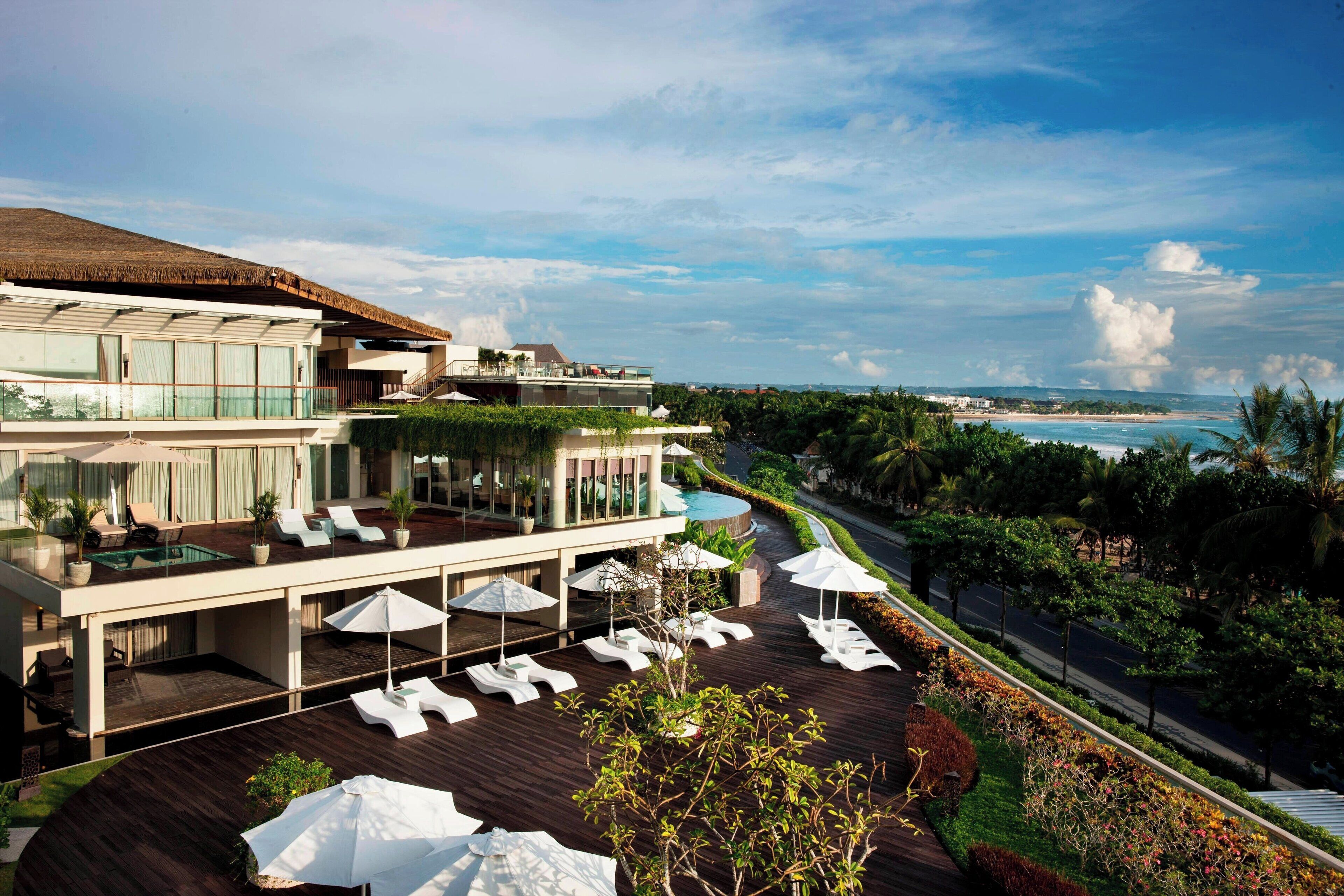 Um resort com área de piscina, espreguiçadeiras e vista para o oceano.