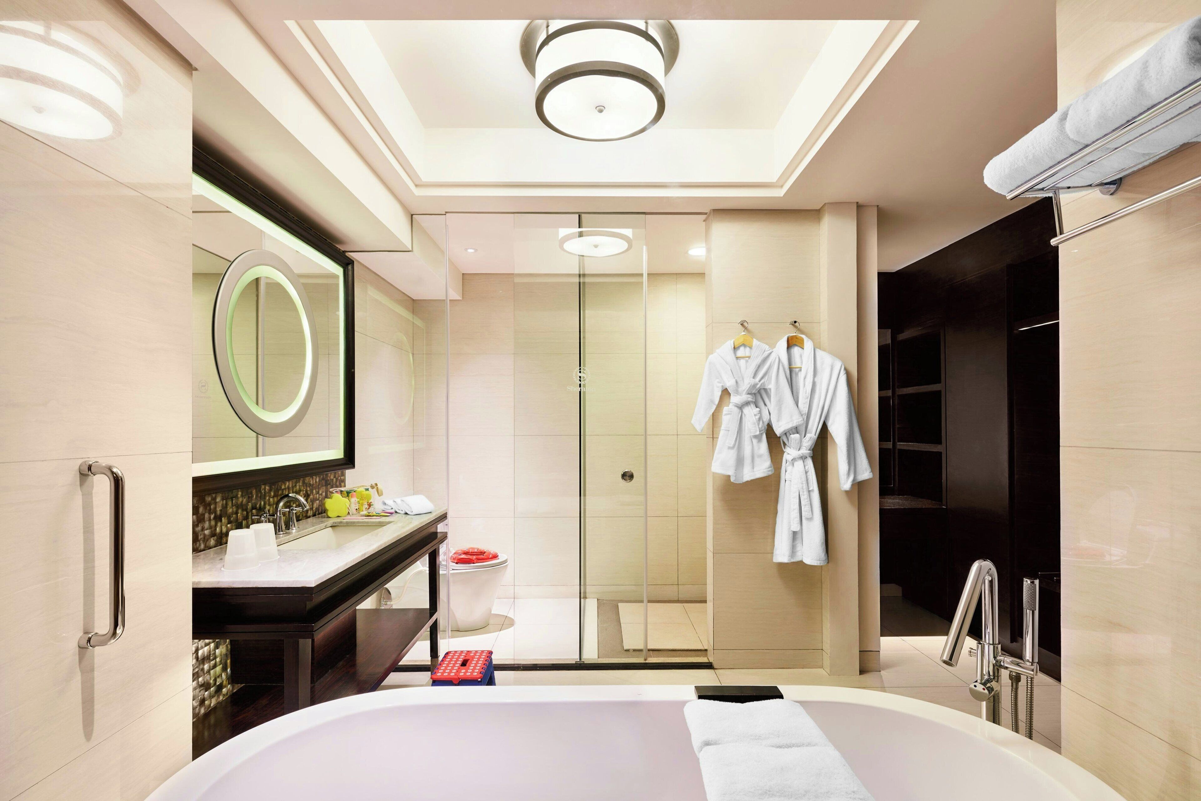 Ein modernes Badezimmer mit einer großen Badewanne, einer Duschkabine und einem Waschtisch mit Spiegel.