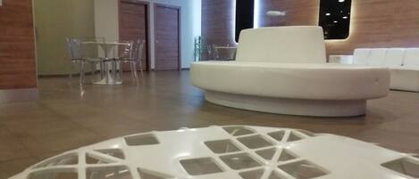 Un interior moderno con un sofá blanco, una mesa de vidrio y un comedor con sillas.