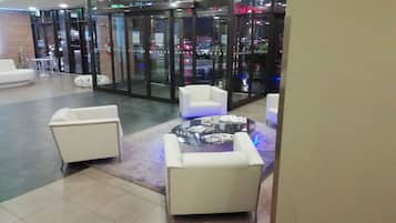 A lobby with a glass partition, white sofas, and a round coffee table.