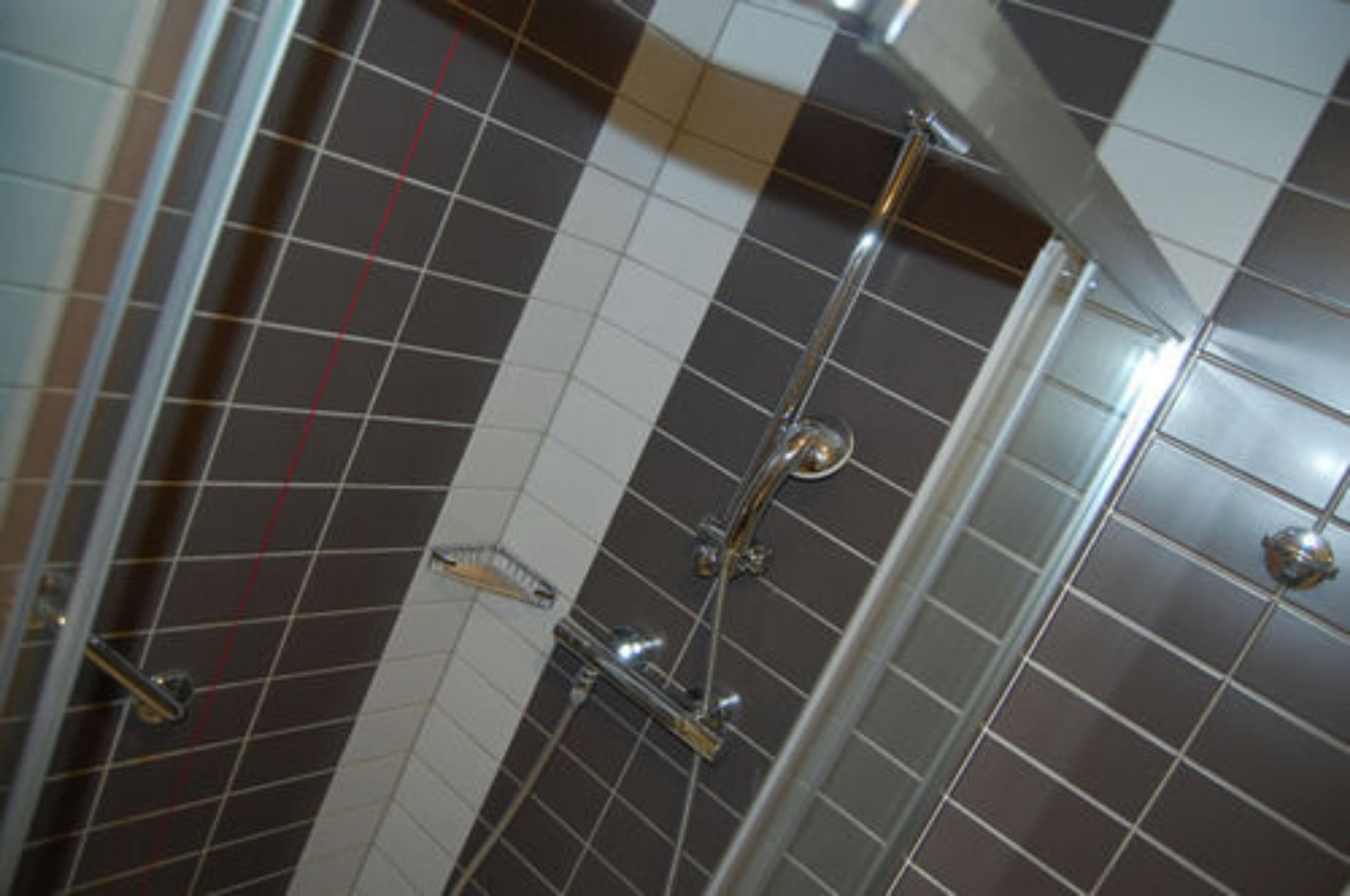 A tiled shower area with a glass door and a chrome showerhead.