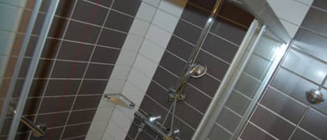 A tiled shower area with a glass door and a chrome showerhead.