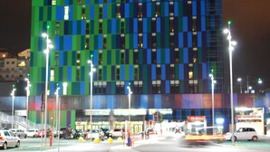 Et hotel med en moderne facade, kendetegnet ved et mønster af vinduer og oplyst skiltning.