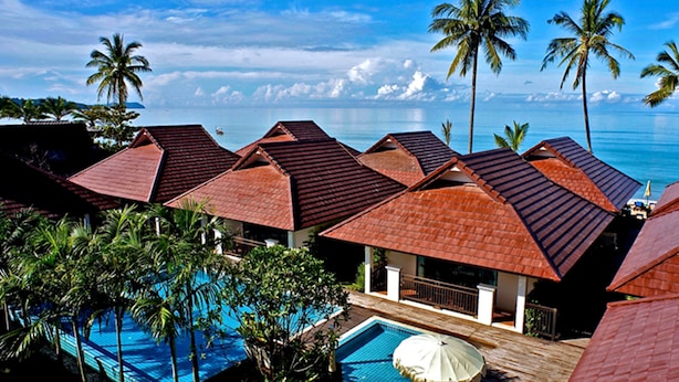 Un resort con varias edificaciones, una piscina y palmeras.