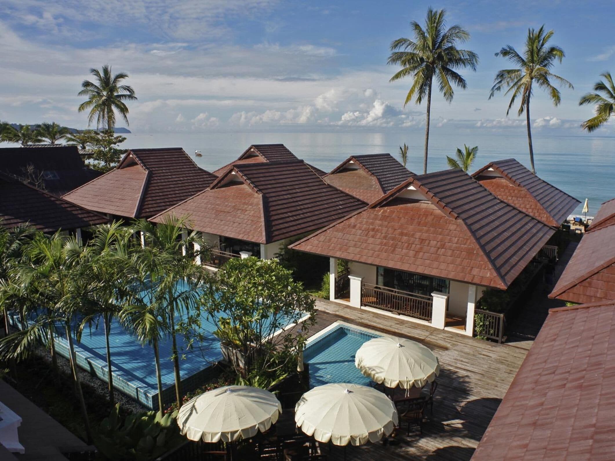 A resort with multiple buildings, a swimming pool, and palm trees.