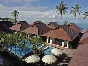 Een resort met meerdere gebouwen, een zwembad en palmbomen.