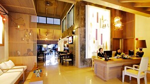 Un moderno vestíbulo de hotel con recepción, zona de estar y comedor.