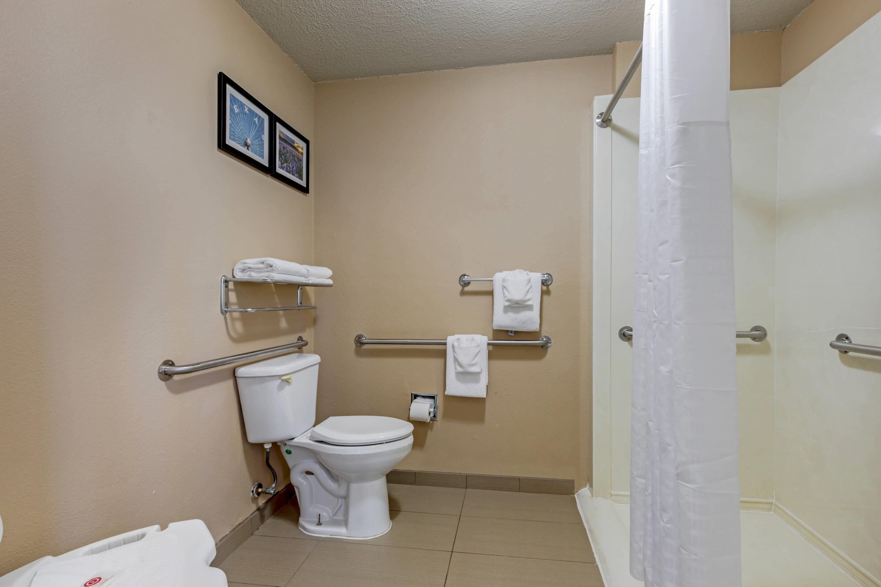 A standard hotel bathroom with a toilet, bidet, towel racks, and a shower curtain.