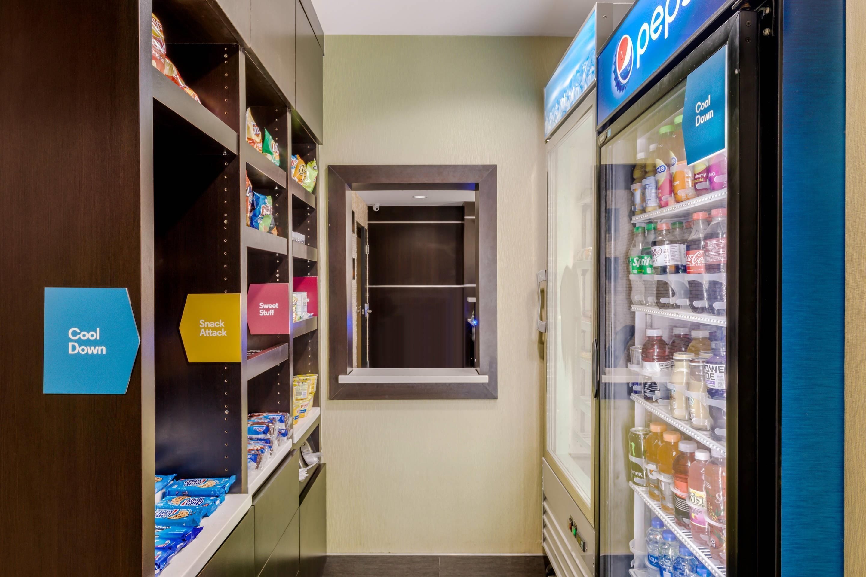 A corridor with snack shelves, a Pepsi refrigerator, and a 'Cool Down' sign.