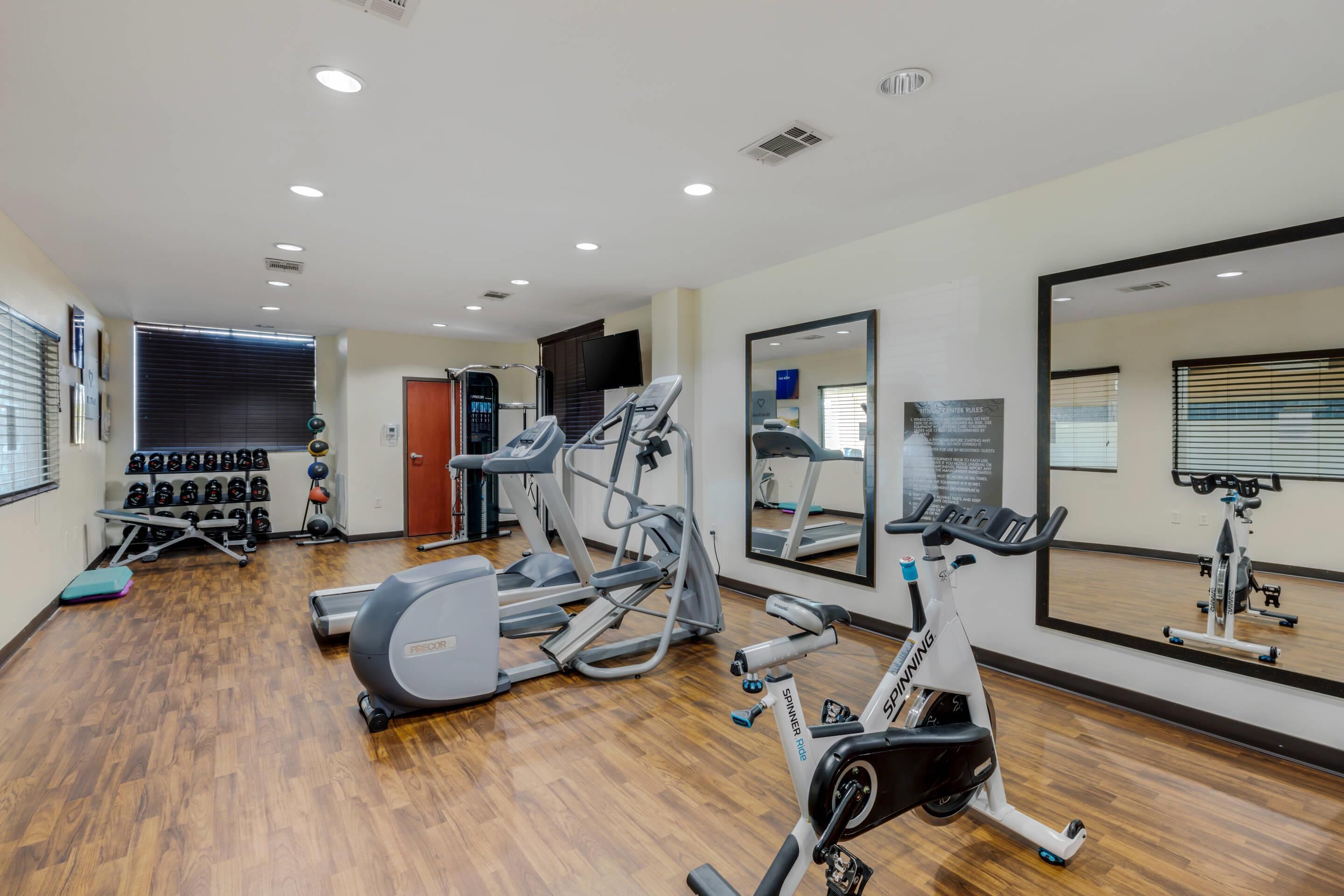A gym with treadmills, stationary bikes, and weights.