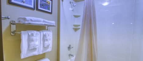 A bathroom with a toilet, a bathtub, and a shower. There are towels hanging on a rack and a shower curtain.
