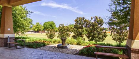 Un espacio al aire libre con bancos, una fuente y un jardín ajardinado.