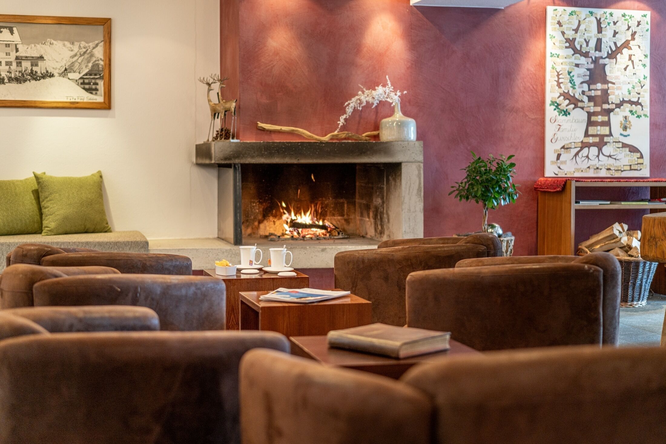 A cozy lounge area with a fireplace, comfortable seating, and a decorative tree wall art piece.