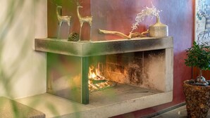 A fireplace with decorative deer figurines and a vase of flowers. - Hotel Hochsölden (Soelden)