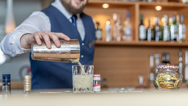A bartender pouring a drink into a glass. - Hotel Hochsölden (Soelden)