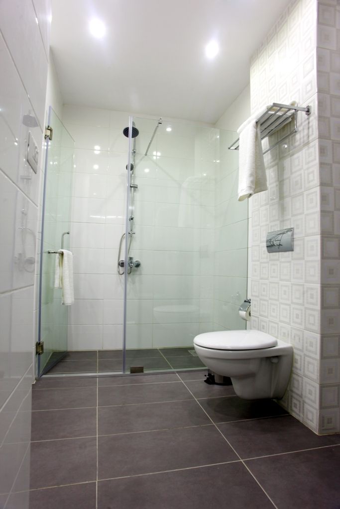 A modern bathroom with a glass-enclosed shower, a toilet, and patterned tiles.
