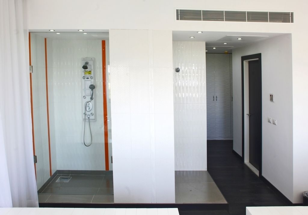 A modern bathroom with a glass-enclosed shower, a visible water heater, and a tiled floor.