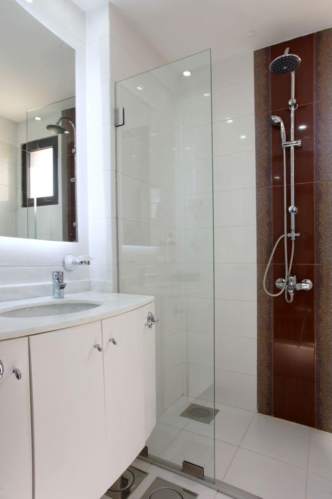 A modern bathroom with a glass-enclosed shower, a white vanity with a mirror, and a tiled floor.