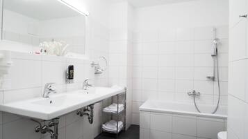 Ein modernes Badezimmer mit zwei Waschbecken, einem Spiegel, einer Dusche und einer Toilette.