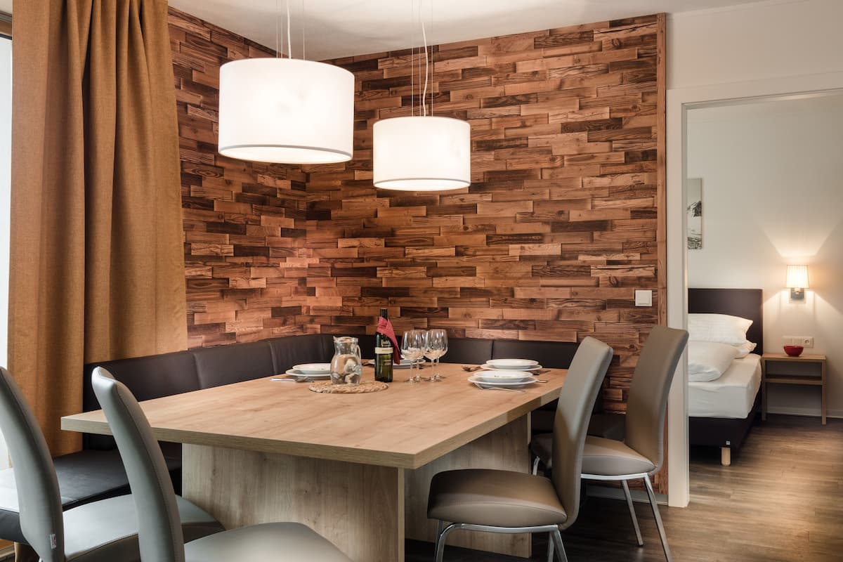 Un espace repas comprenant une table en bois, des chaises et des luminaires suspendus.