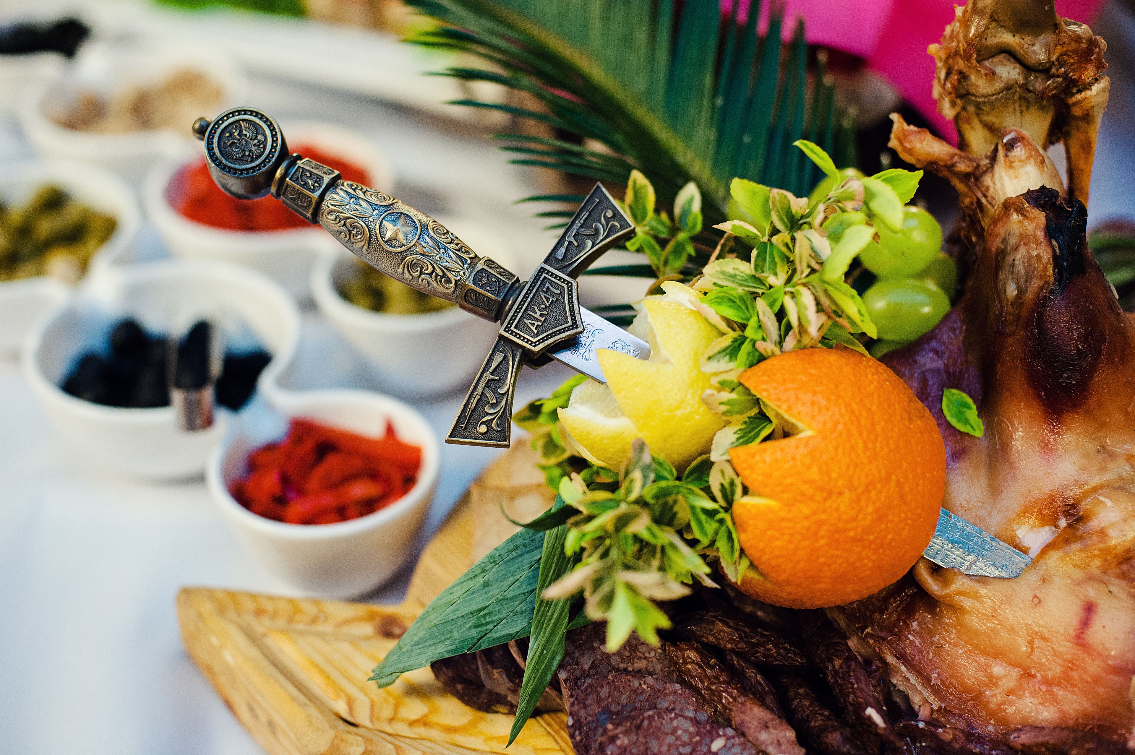 A ceremonial meal with a decorated knife, roasted meat, and various condiments.