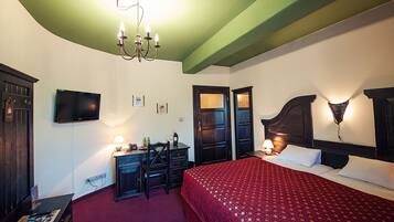 Une chambre d’hôtel équipée d’un lit, d’un bureau, d’une chaise et d’un téléviseur fixé au mur.