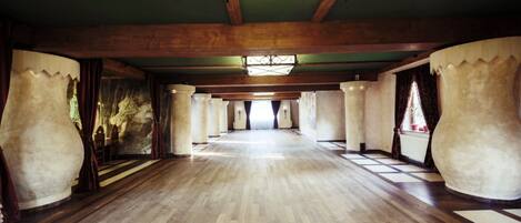 A spacious room with wooden floors, large columns, and a high ceiling with a skylight.