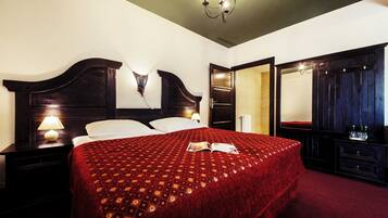 Una habitación de hotel con una cama grande, una mesita de noche con lámpara, un armario y un espejo.