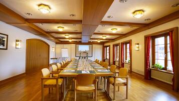 A conference room with a long table, chairs, and a projector screen.