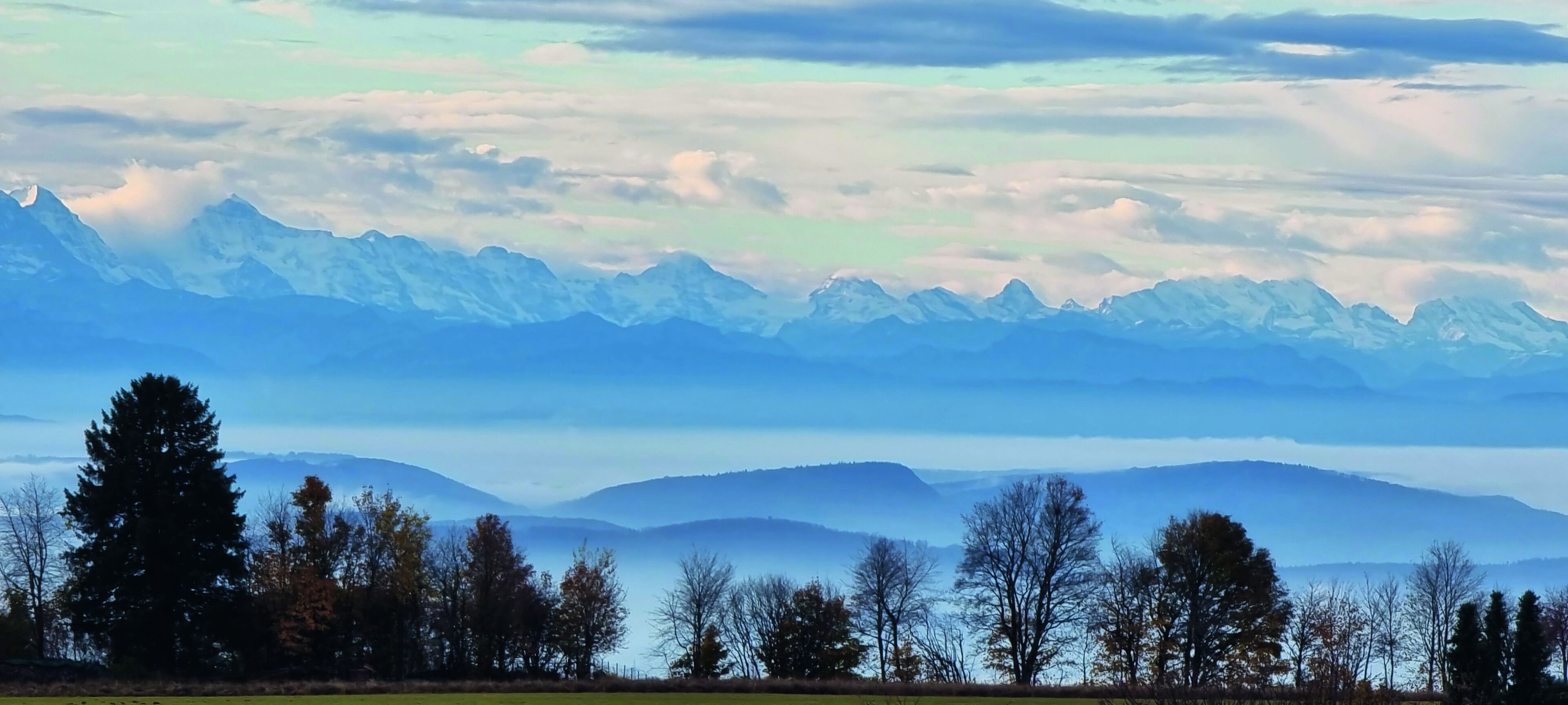 Eine Berglandschaft mit blauem Himmel und Blick auf ferne Gipfel.