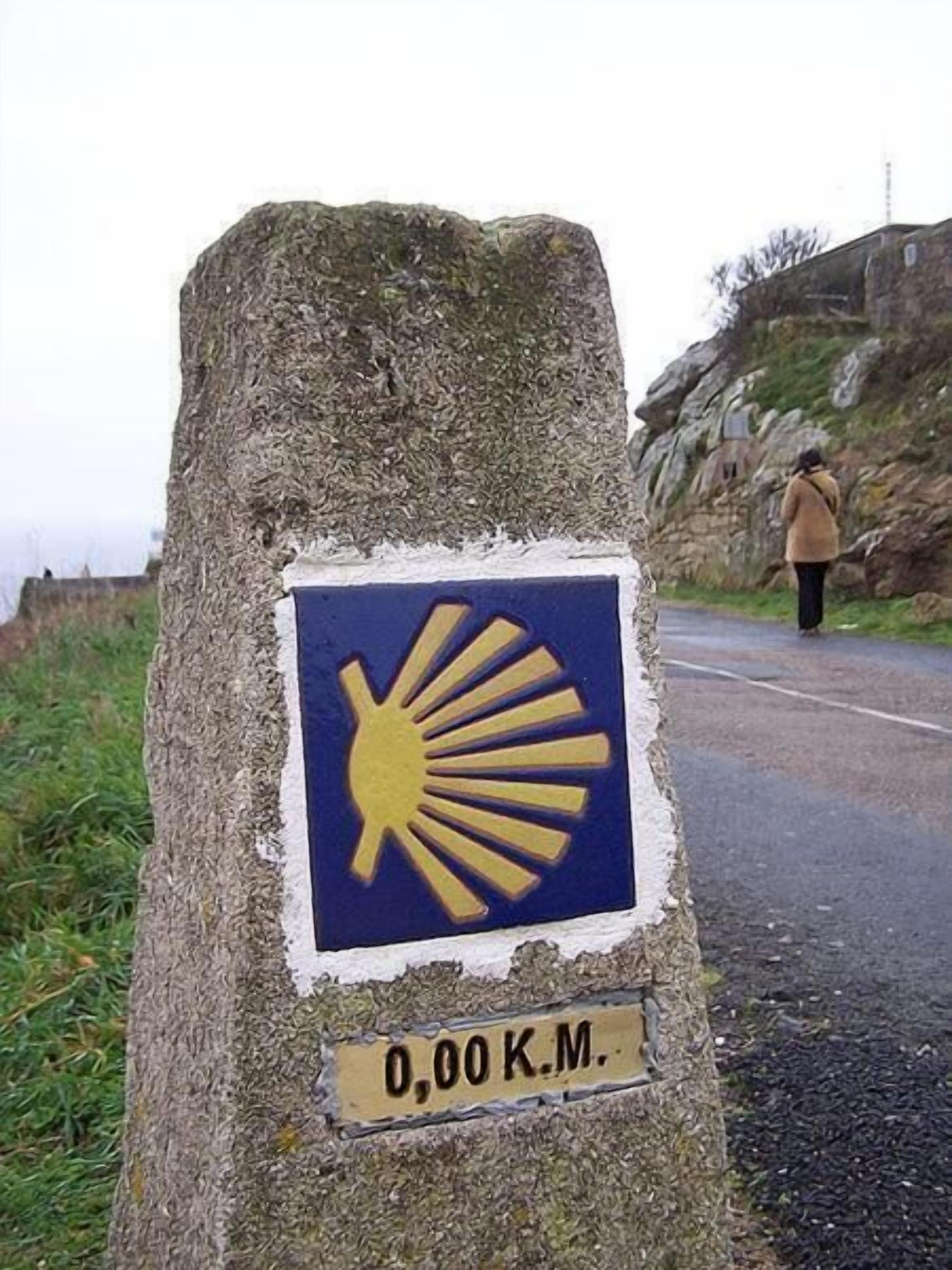 A stone marker with a sun symbol and a distance marker of 0.00 K.M.