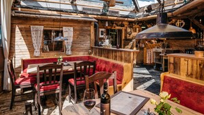 A cozy wooden interior with a bar area, seating, and a table with a wine bottle and menu. - AlpenParks Hotel Montana Matrei (Matrei in Osttirol)