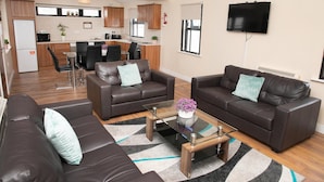 A modern living room with two leather sofas, a glass coffee table, and a kitchen in the background. - Arch House Apartments (Athlone)