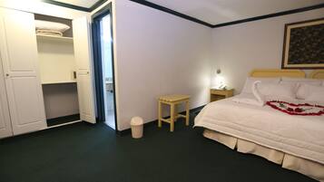 A bedroom with a bed, bedside table, lamp, and an open closet.