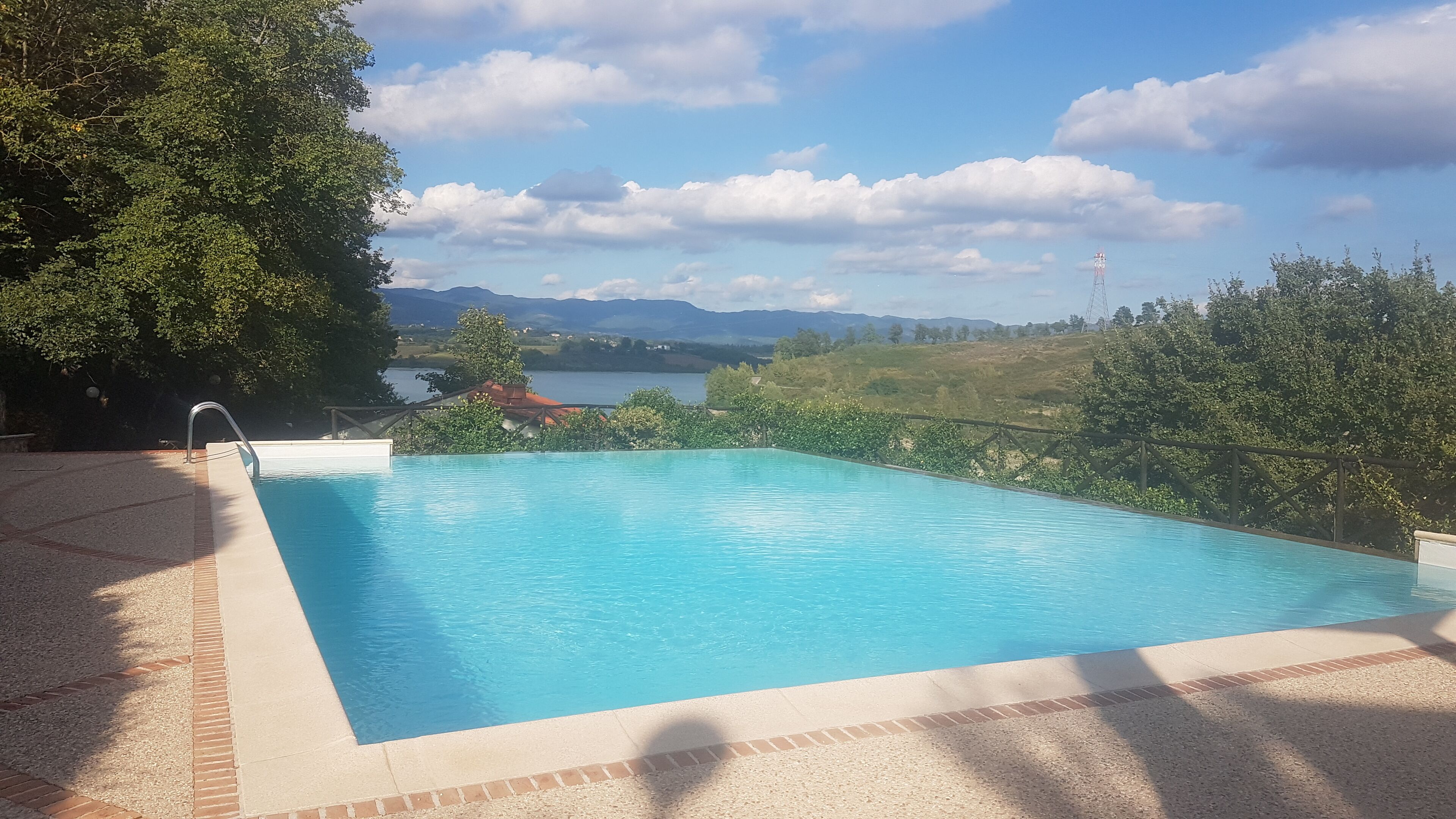 A rectangular swimming pool with a clear view of a lake and mountains in the background.