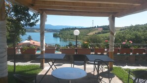 Un espace extérieur aménagé avec des tables et des chaises, offrant une vue sur un lac et des collines.