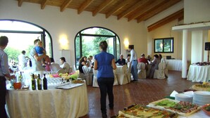 Un espace repas avec des tables rondes recouvertes de nappes blanches, diverses sortes de plats et des bouteilles de vin.