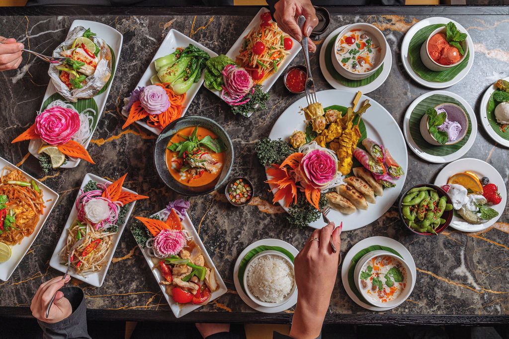 A table with various dishes, including a plate with a fish head, a bowl of soup, and several plates with vegetables and rice.