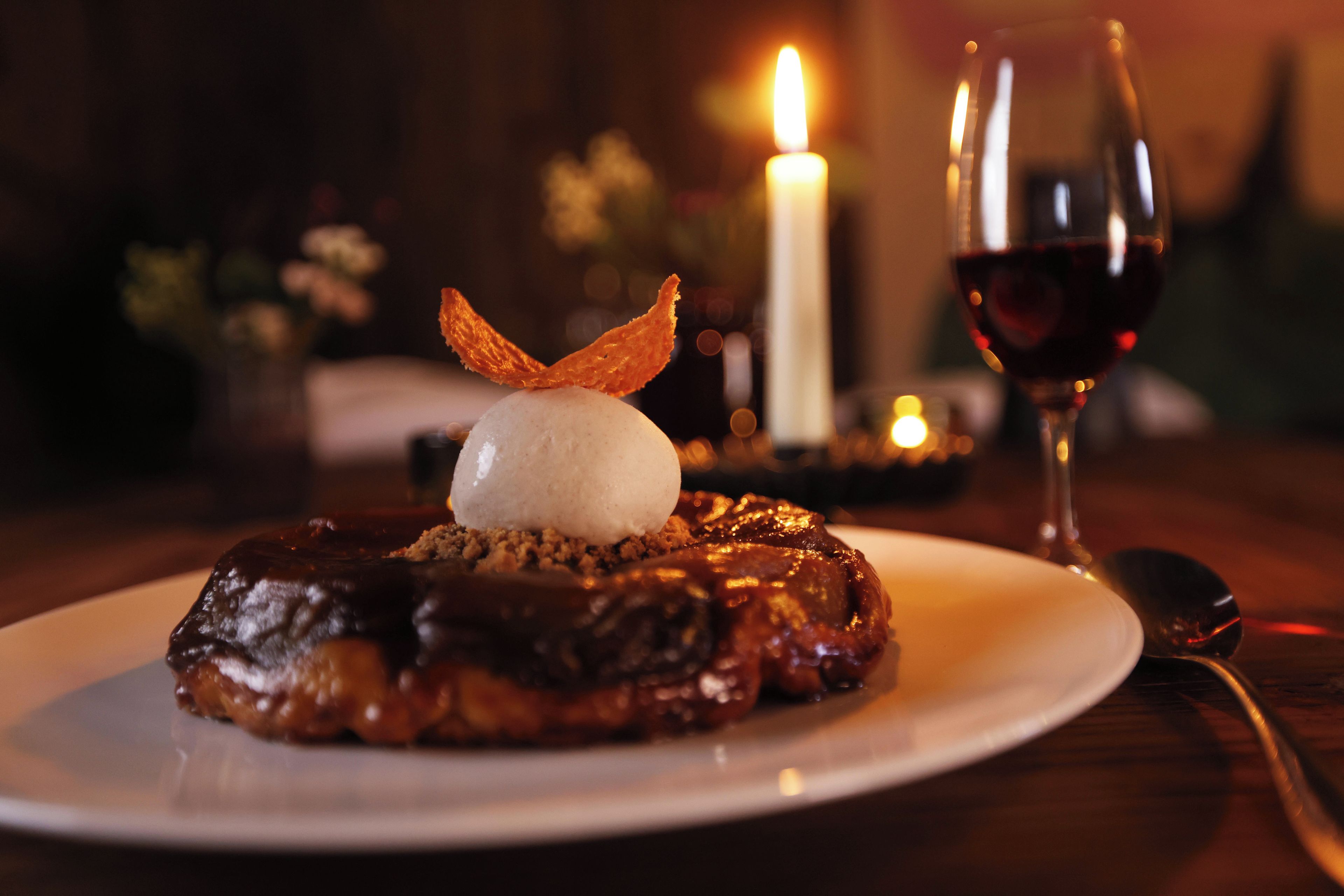 A dessert plate with a chocolate-covered pastry, a scoop of ice cream, and a decorative orange leaf on a white plate.