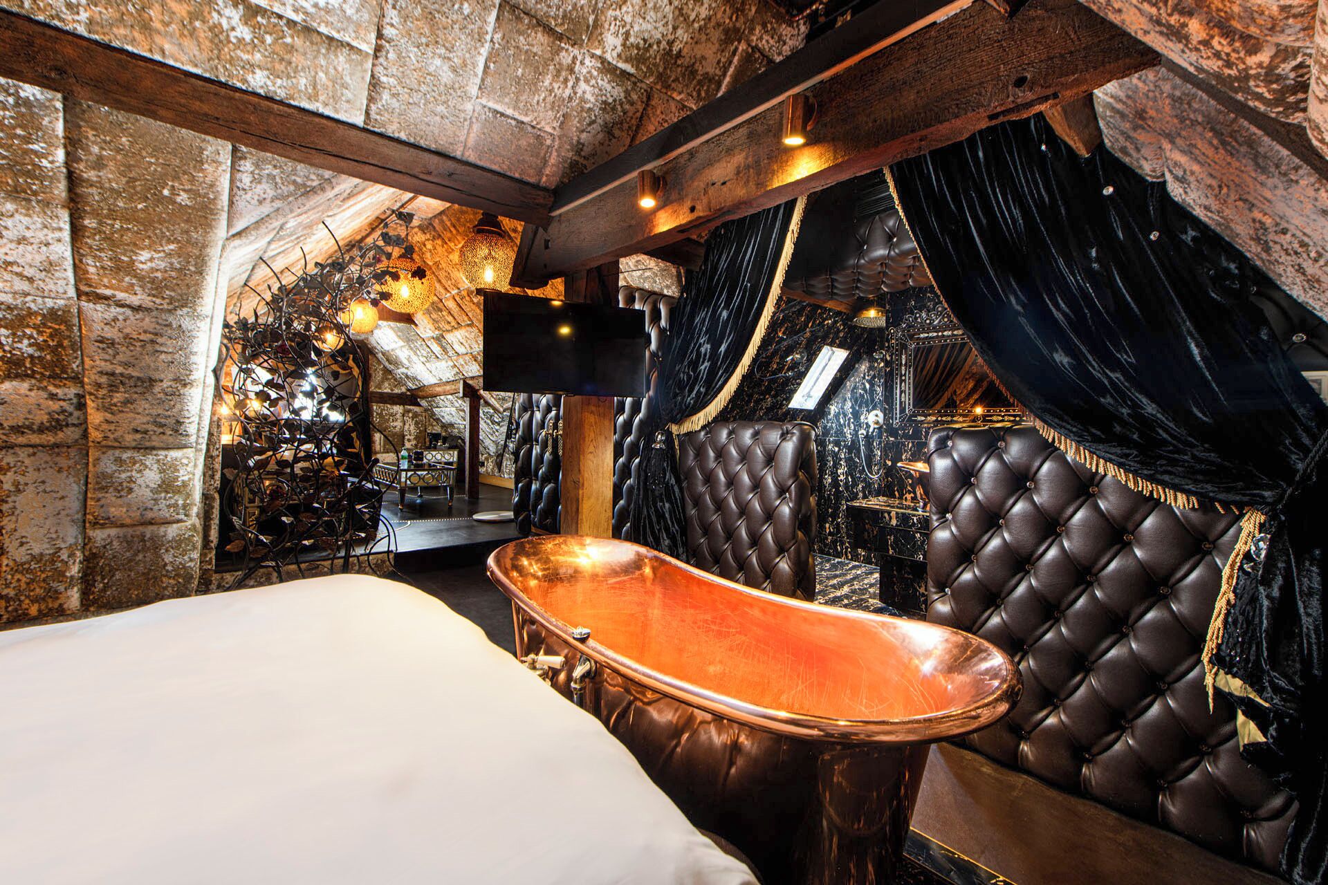 A luxurious room with a large bed, a bathtub, and a leather sofa.