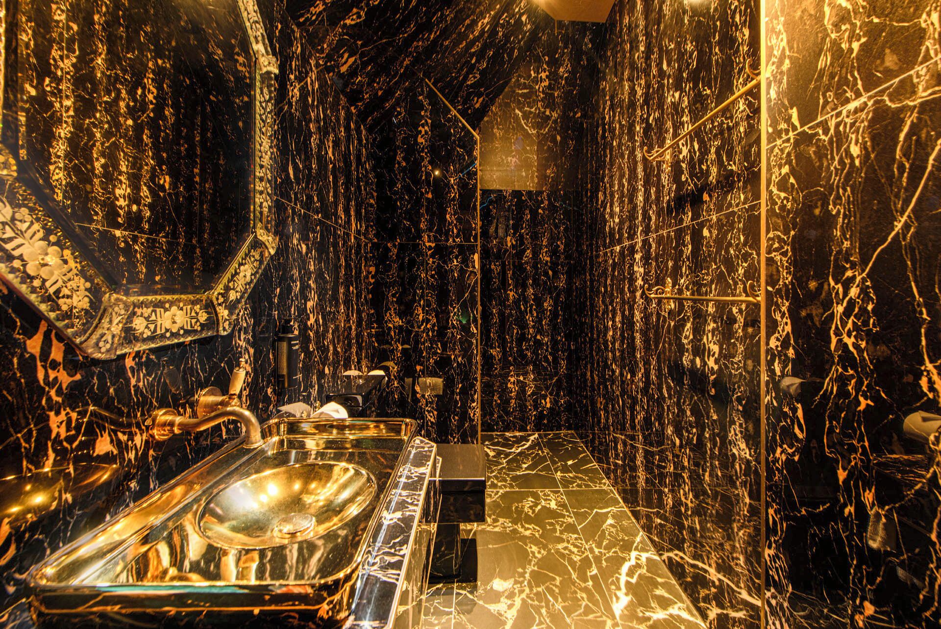A bathroom with a marble floor, a sink, and a mirror.