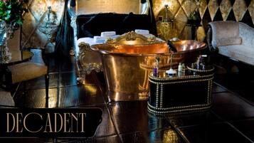 Relax in a classic bedroom with a large bed, gold bathtub, and elegant side table.