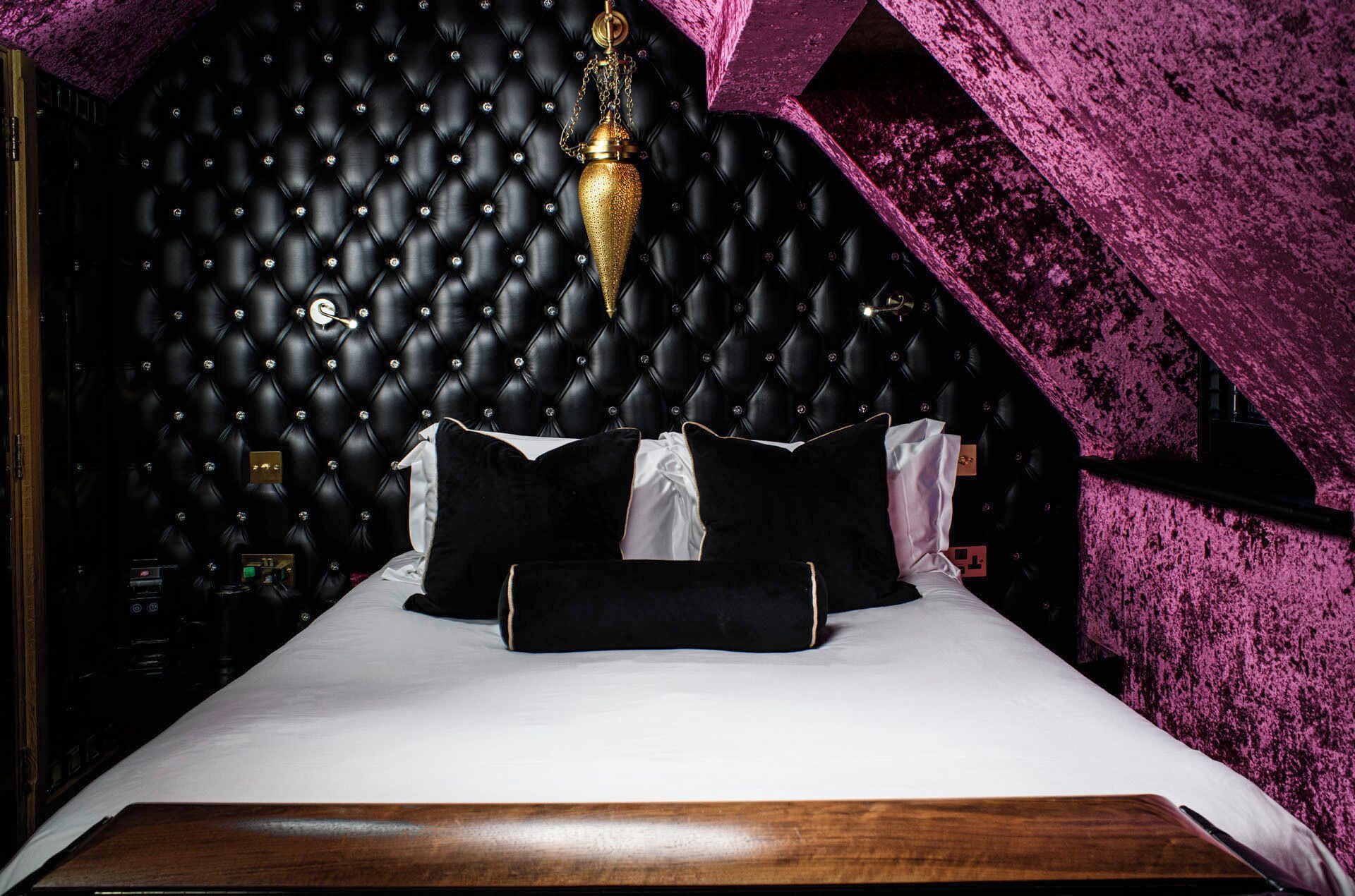 A bed with a tufted headboard, a bedside table, and a decorative hanging light fixture.