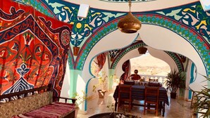 A room with a patterned wall, a round table with decorative items, a sofa, and an archway leading to a balcony. - Cleopatra Hotel Luxor (Luxor)