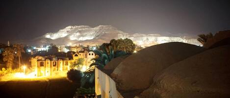 Vista nocturna de una montaña con un edificio iluminado en primer plano.